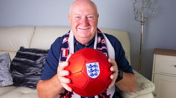 Tommy Dunne smiling, holding a red football