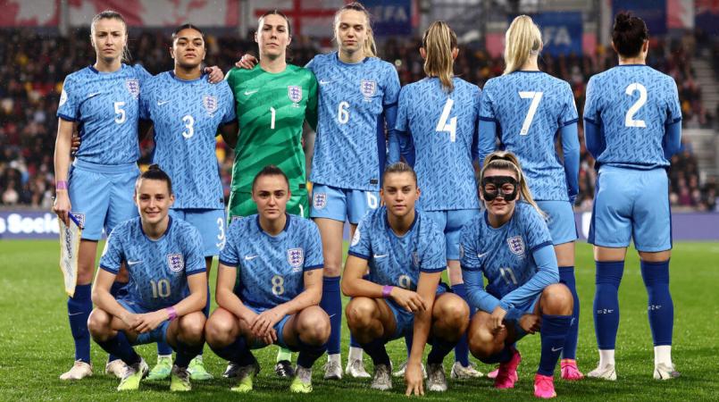 The England women's team stand together wearing shirts without their names on