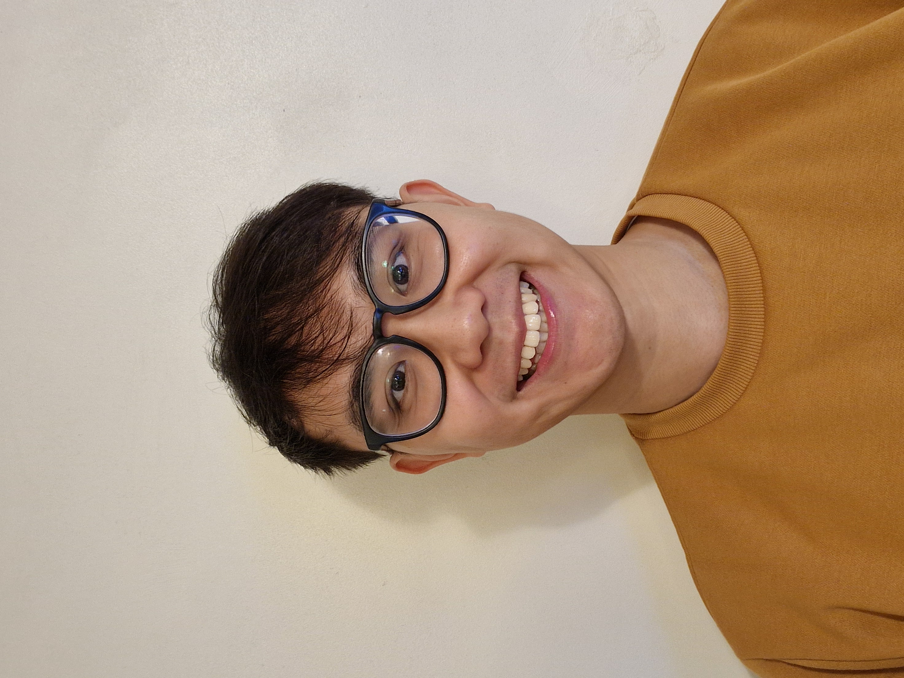 A young smiling man with glasses.