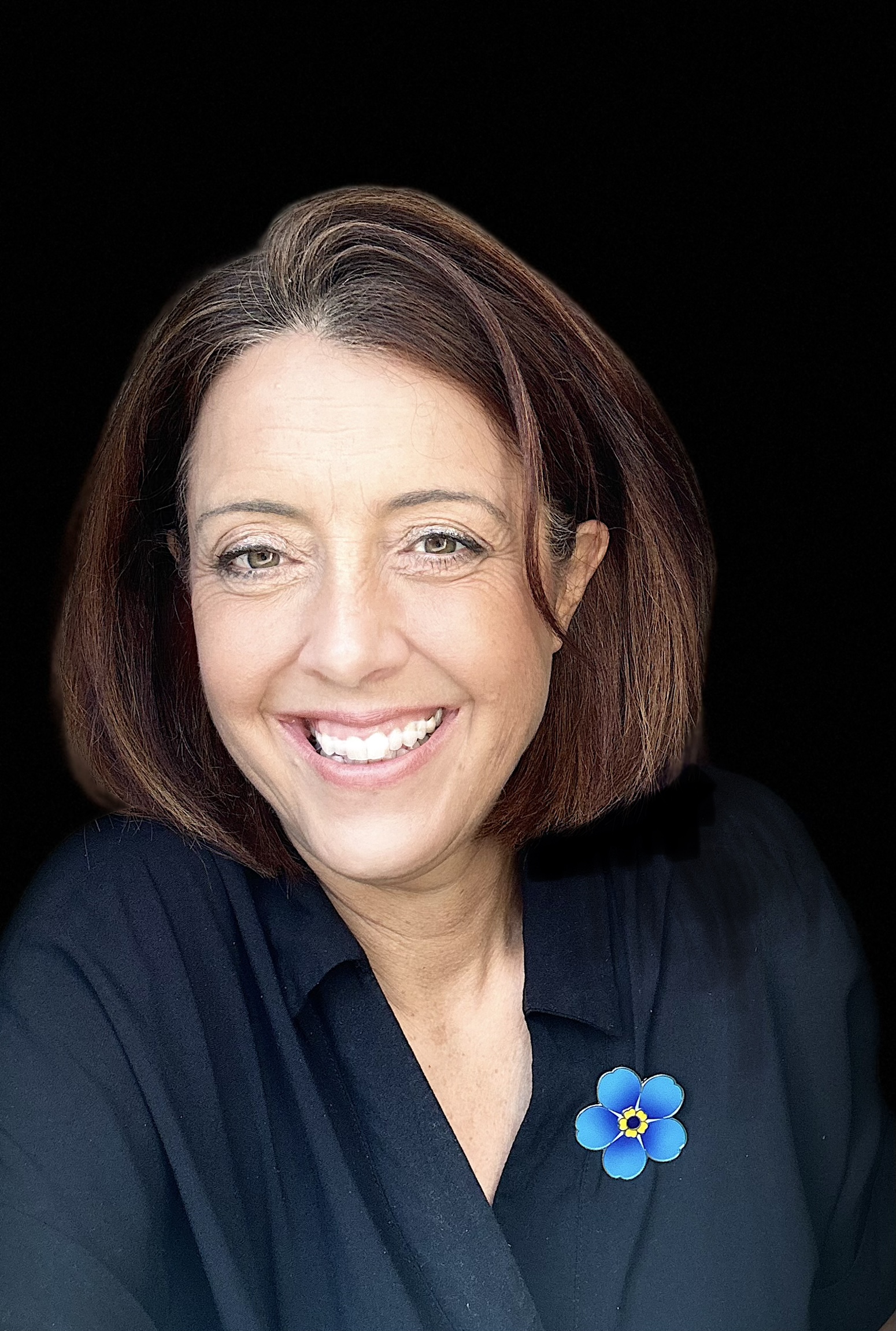 Photo of Alzheimer's Society Chief Executive Kate Lee. Kate is smiling and wearing an Alzheimer's Society Forget Me Not flower brooch