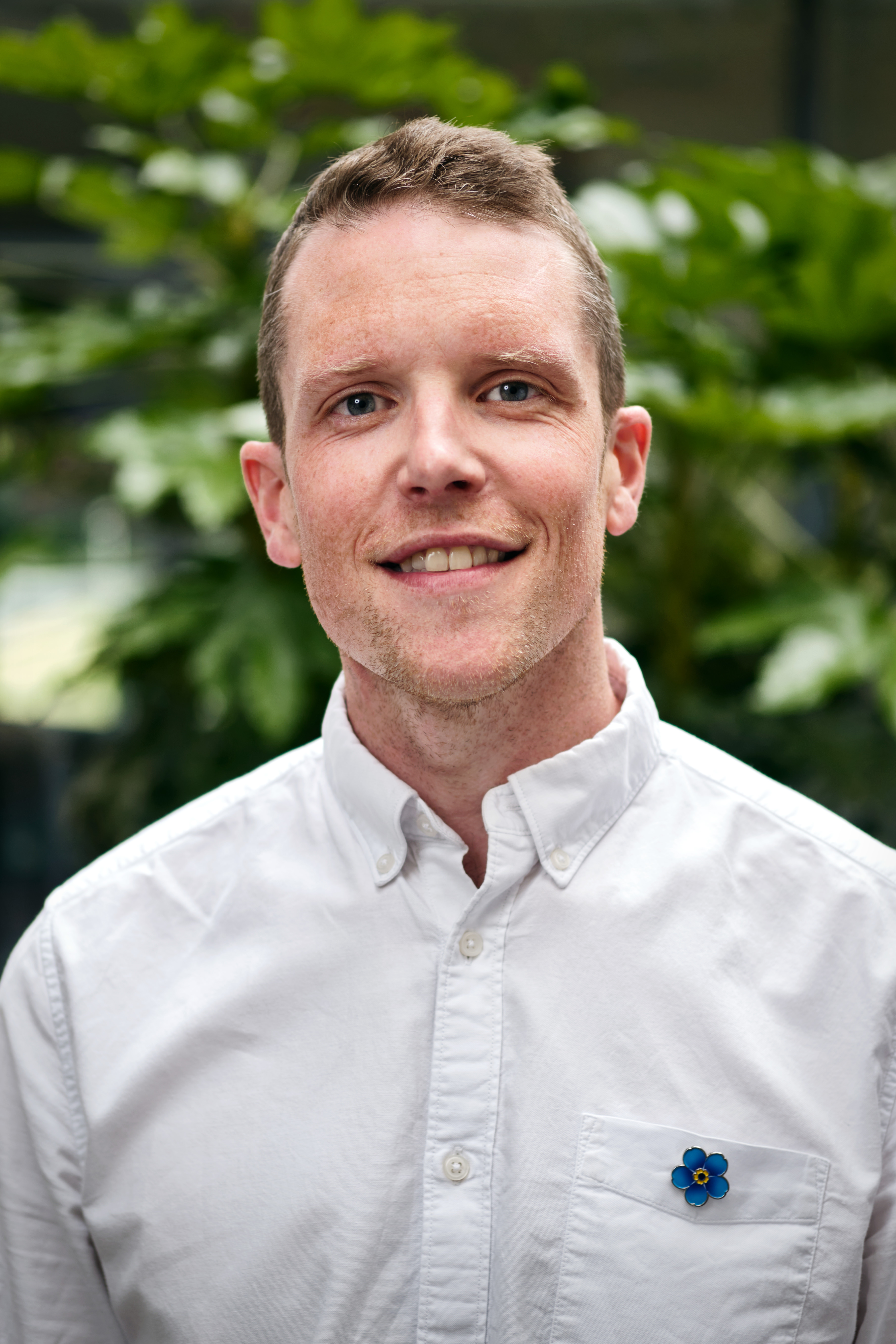 Photo of Alzheimer's Society Associate Director of Evidence, Policy and Influencing Mark MacDonald. Mark is smiling and wearing an Alzheimer's Society Forget Me Not flower pin badge