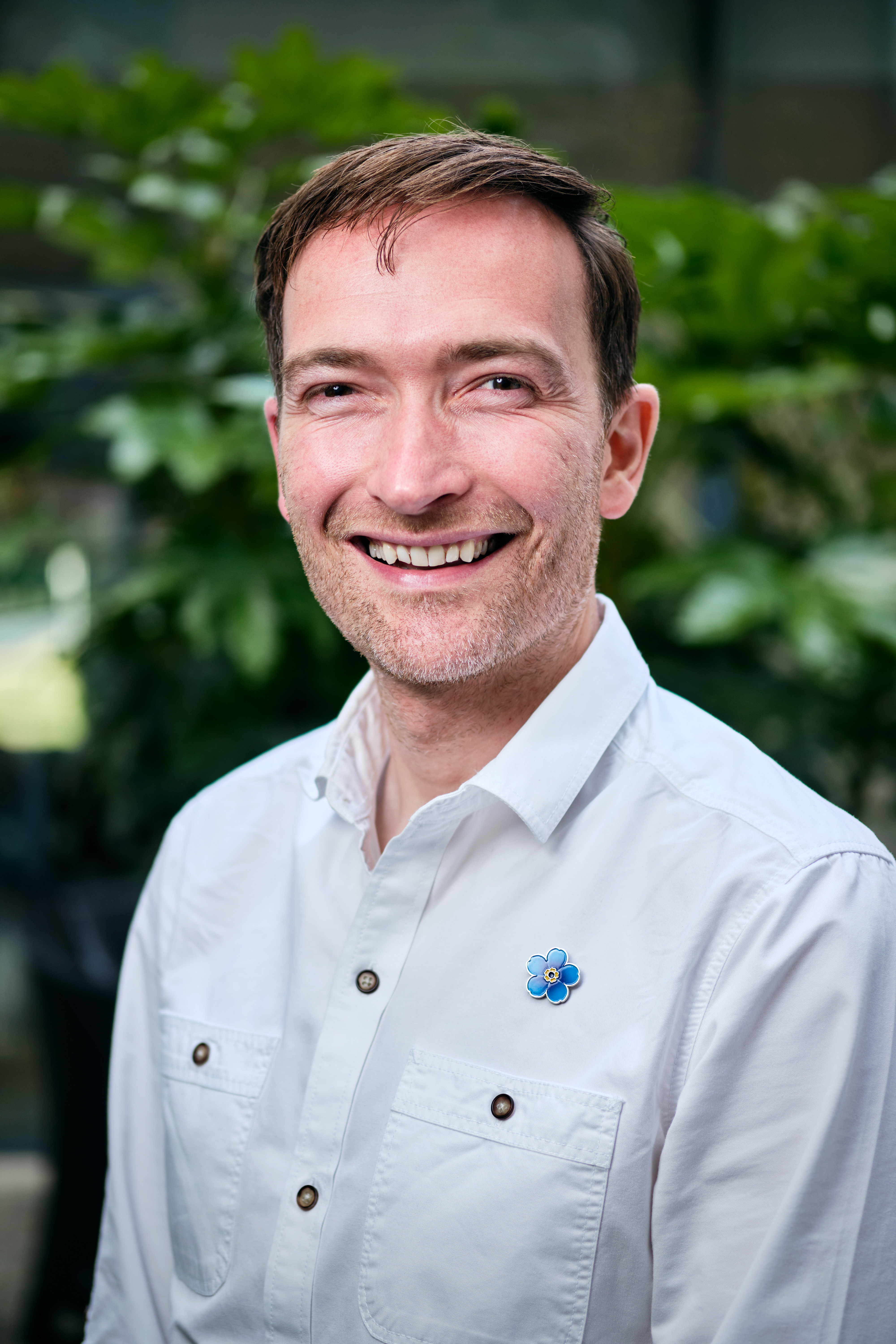 Photo of Alzheimer's Society Associate Director of Research and Innovation. Richard is smiling and wearing an Alzheimer's Society Forget Me Not flower pin badge