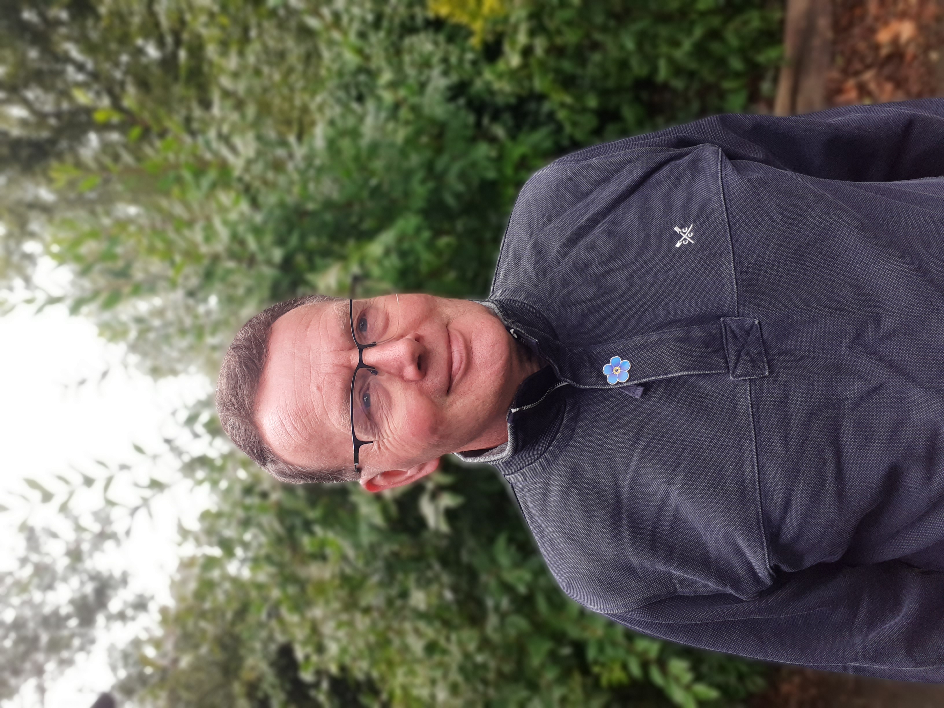 Photo of Alzheimer's Society Head of Knowledge and Learning Tim Beanland. Tim is smiling and wearing a an Alzheimer's Society Forget Me Not pin badge