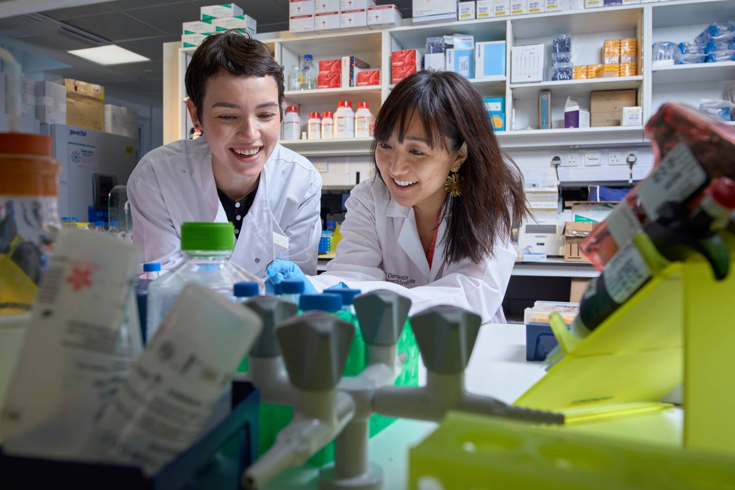 Two scientists examining a microscope slide together in a laboratory setting.