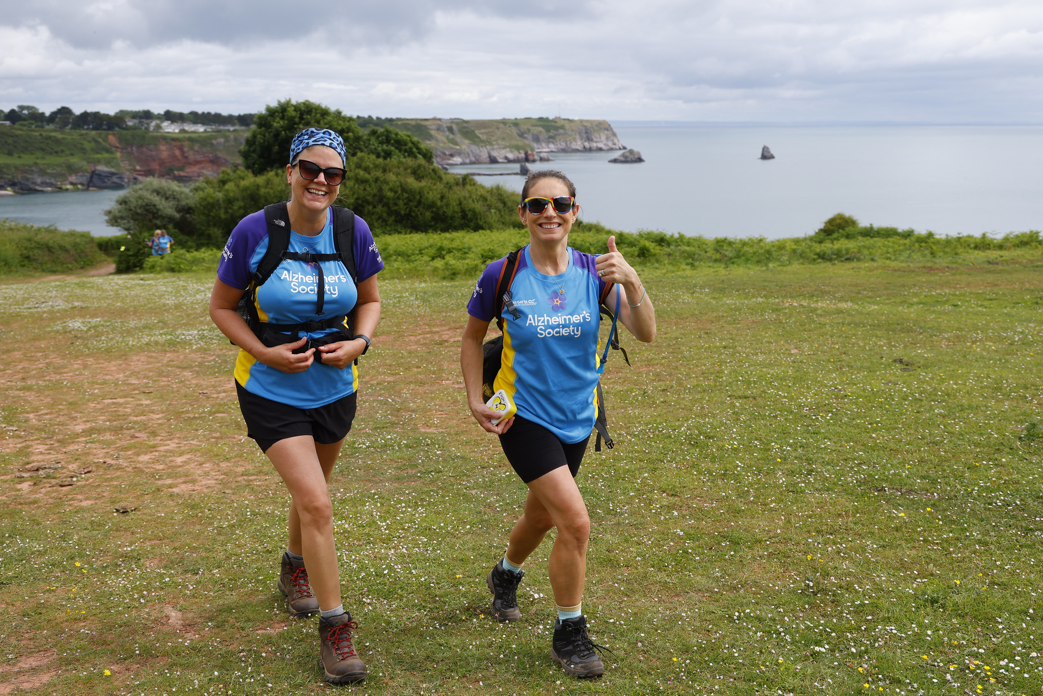 two people trekking with coastline in background