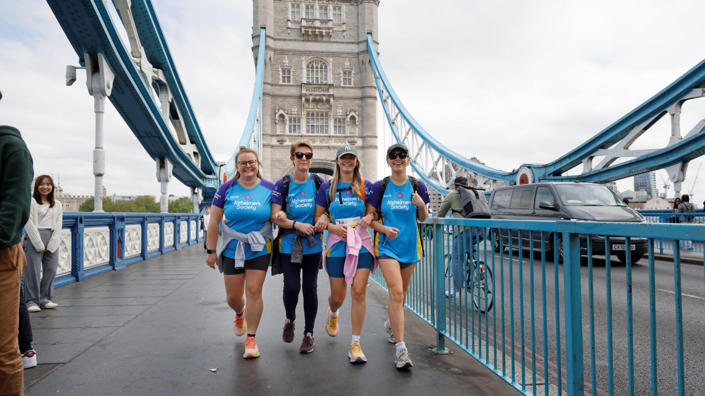 4 trekkers walking over a London bridge