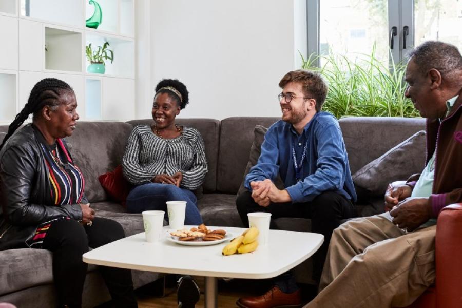 Four people relaxed in conversation on a sofa sitting around a table