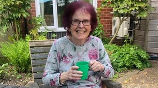 Neil's mum smiling holding a mug of tea