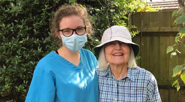 Ellie, a care home worker, wearing a face mask and standing beside a resident