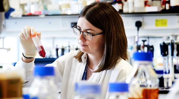 A female research looking at a tube of liquid