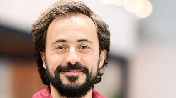 Hugo Fernandes smiling at the camera and wearing a red top