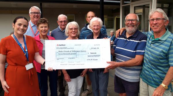 Eight members of Radyr and Morganstown volunteer fundraising group presenting large cheque to Alzheimer's Society