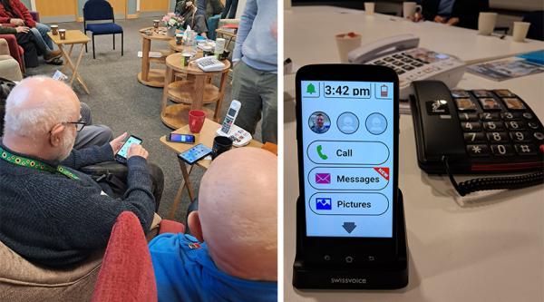 Two men sat in chairs looking at mobile phones and three phones on a table, a mobile and two landlines