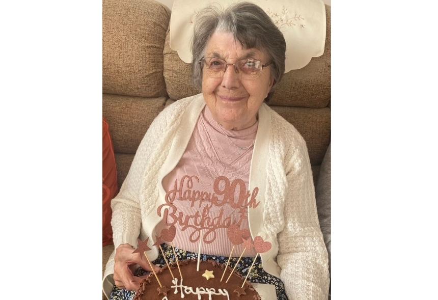 Barbara smiling at the camera while holding her 90th birthday cake