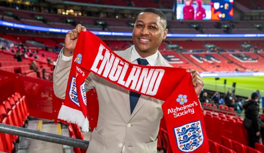 Rickie holding an England scarf with the Alzheimer's Society logo on it