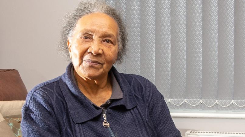 Mavis Blake, an older woman of colour, is smiling towards the viewer