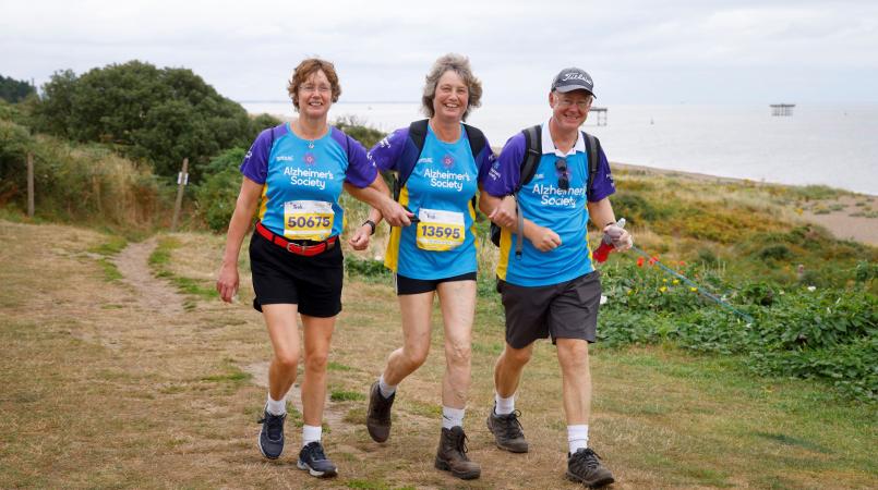 Group of three trekkers walking along a coastline