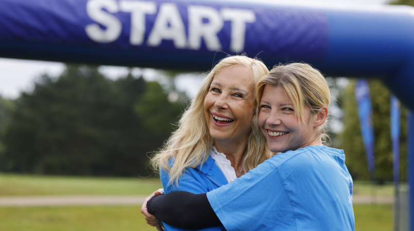 Mother and daughter in Memory Walk t-shirts, tightly hugging and smiling in front on the start line