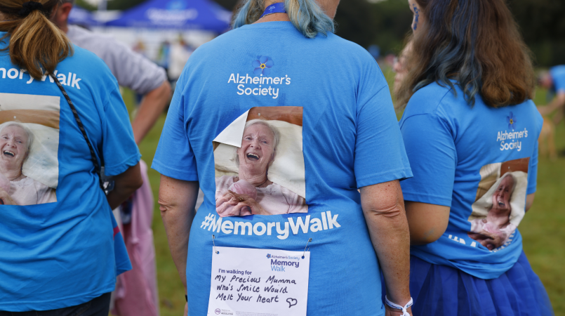 3 people in Memory Walk t-shirts, with a picture of a loved one and message on their backs.