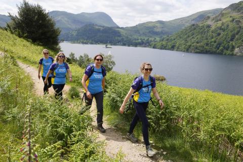 Four trekkers walking in front of a lake