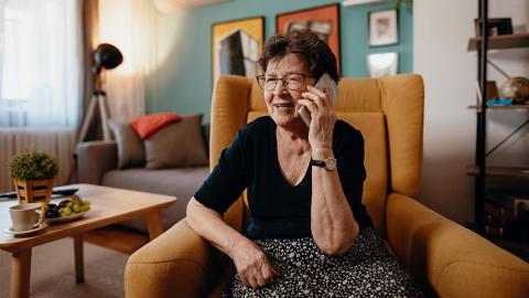 A woman sit in her living room on her mobile phone