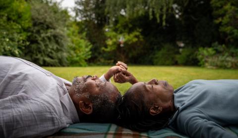 A couple lying on the grass holding hands