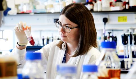 A female researcher looking at a tube of liquid