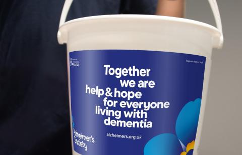 An Alzheimer's Society collection bucket is held up for donations.