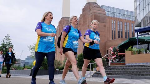 Three women walk past Battersea Power Station wearing Alzheimer's Society t-shirts.