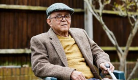 A old man in cap sits in his garden chair.