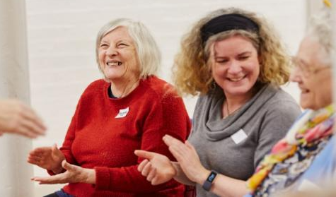 Two women sitting together clapping their hands.